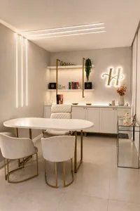 Sala de consulta da Harmonelle Clínica, com mesa oval, cadeiras claras e o H da marca iluminado na parede